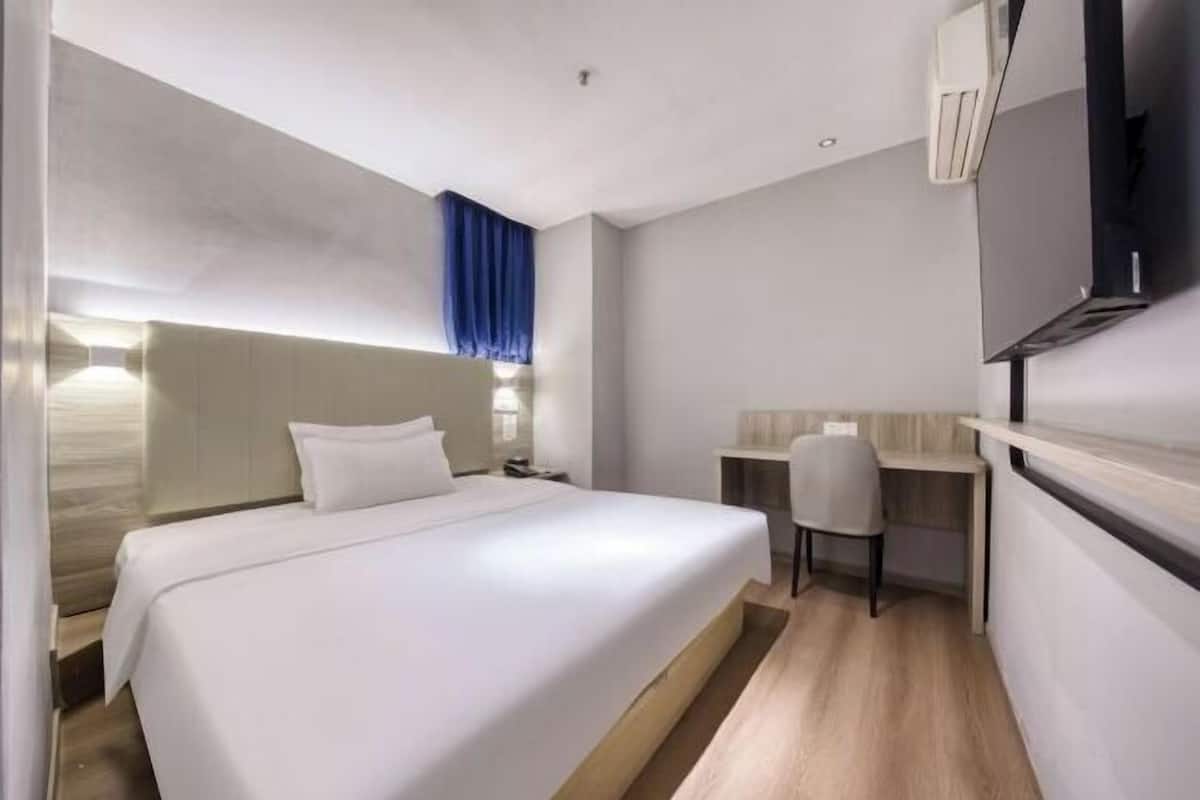 Une chambre d’hôtel moderne, dotée d’un grand lit, d’un bureau et d’une télévision.