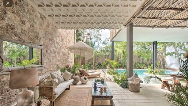 A cozy outdoor seating area with a stone wall, a wooden bench, and a table with a lamp. - Stunning 3 bedroom condo near beach&downtown Tulum (Tulum)
