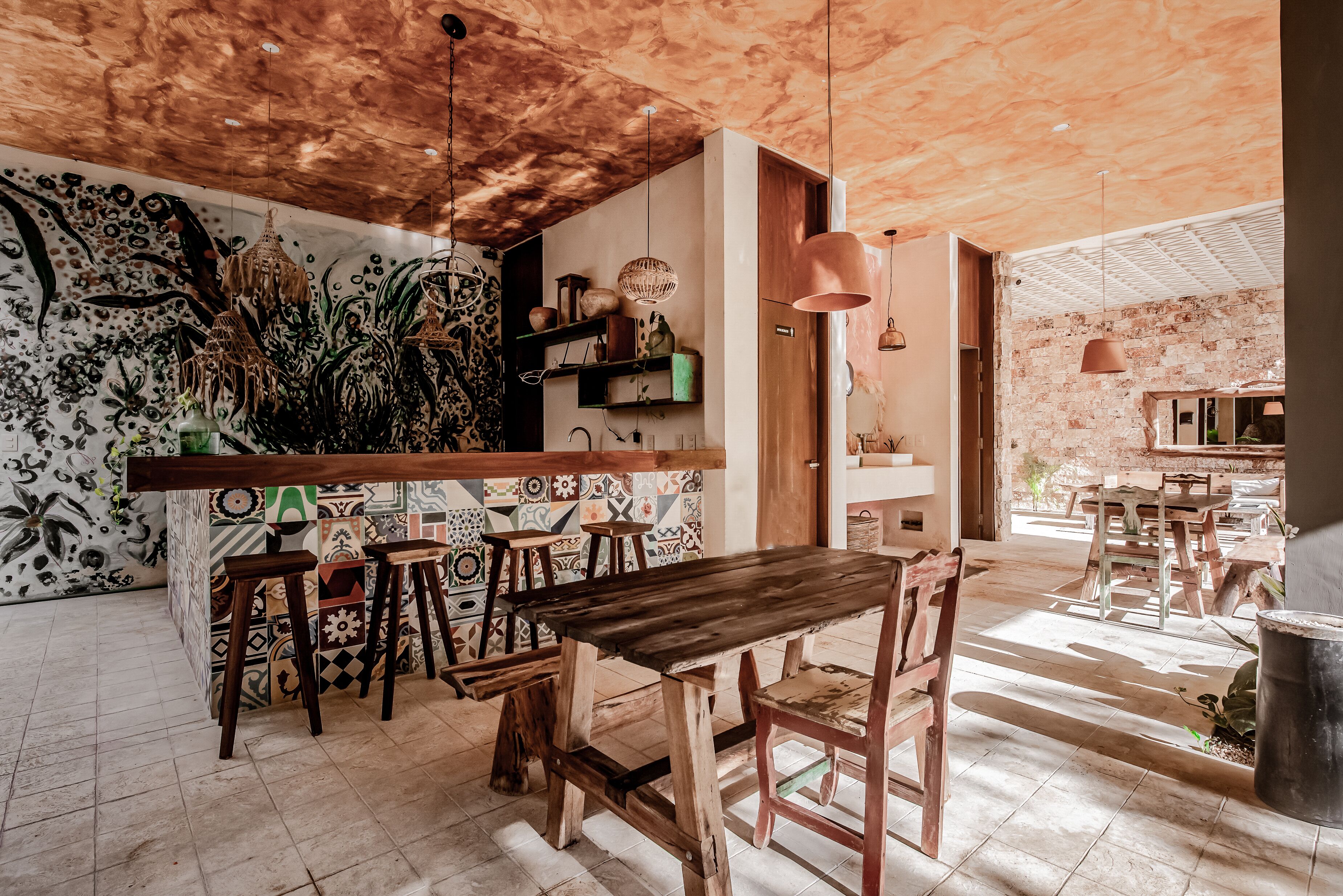 A rustic dining area with wooden furniture, a patterned wall, and hanging lights.