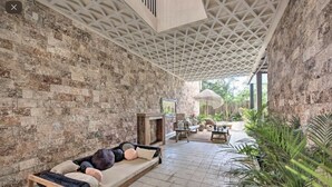 A cozy lounge area with a stone wall, a wooden bench with cushions, and a small table with a lamp. - Stunning 3 bedroom condo near beach&downtown Tulum (Tulum)