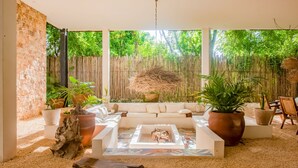 A sunlit patio with a white sofa, a fire pit, and various potted plants. - Stunning 3 bedroom condo near beach&downtown Tulum (Tulum)