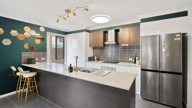 Una cocina moderna con una isla central, electrodomésticos de acero inoxidable y una original decoración de pared hexagonal.