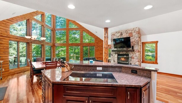A spacious kitchen with a stone fireplace, large windows, and a dining area.