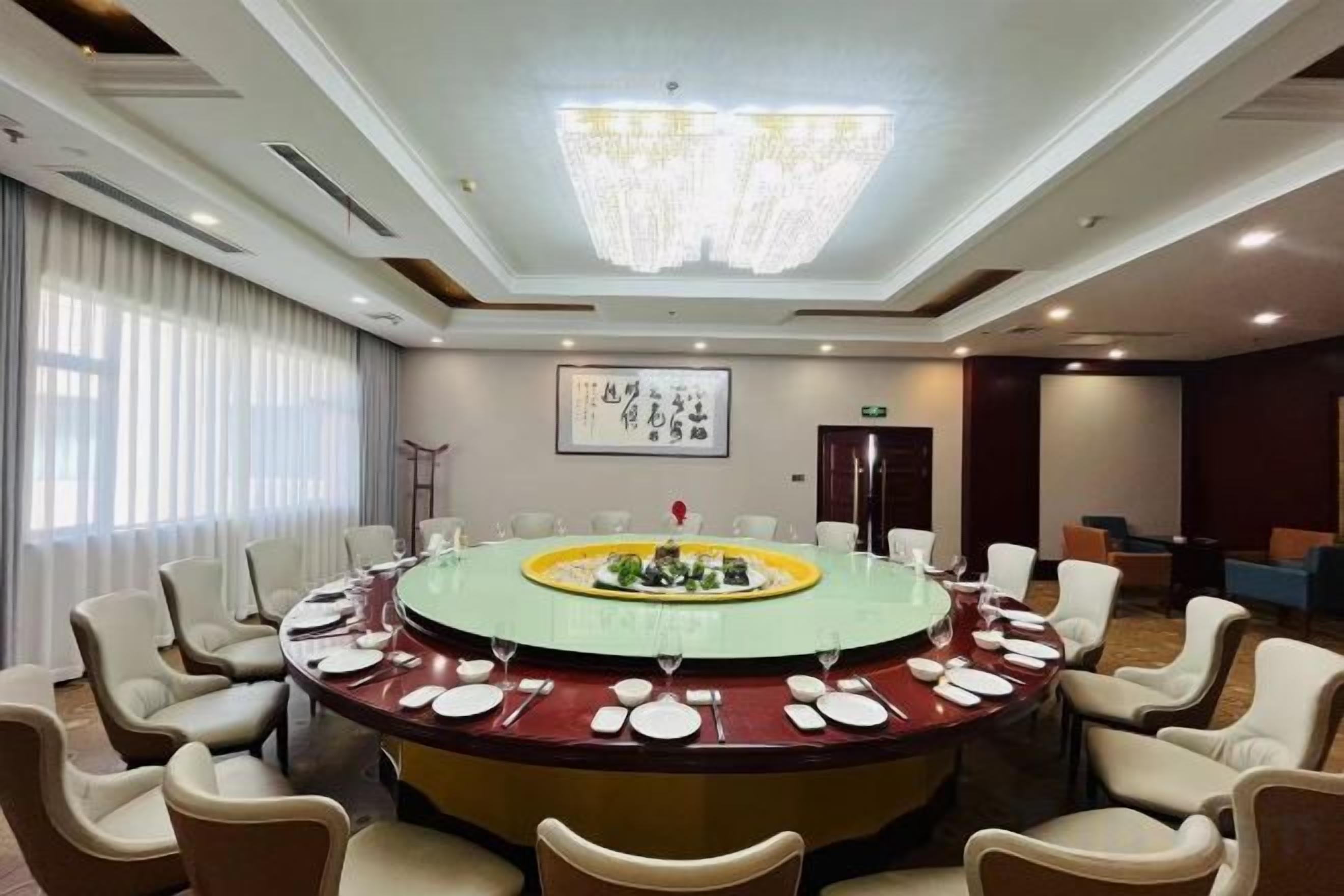 A conference room with a round table, chairs, and a chandelier.