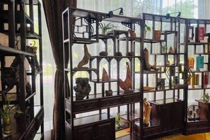 A room with a large window, a wooden bookshelf with various decorative items, and a chair. - Jixi International Hotel (Jixi)