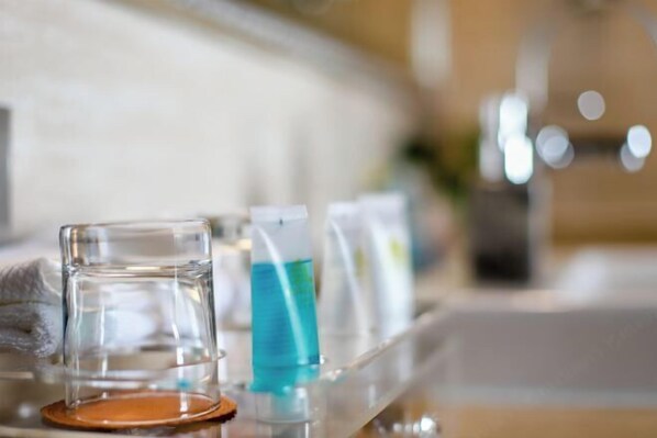 A bathroom counter with a glass of water, a blue bottle, and a white bottle. - Jixi International Hotel (Jixi)