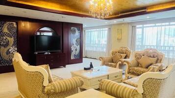 A spacious living room with a television, two sofas, a coffee table, and a chandelier.