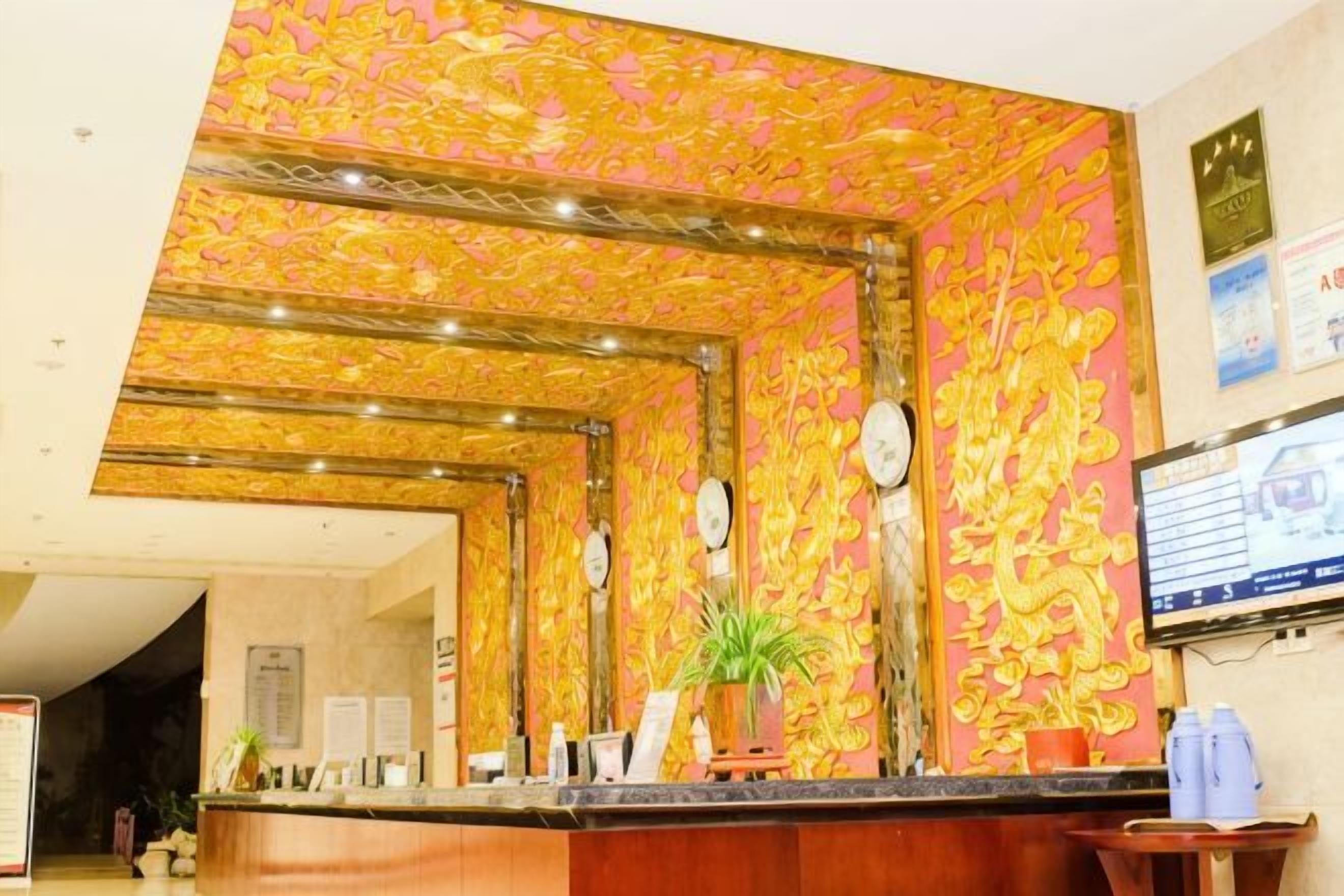 A reception area with a counter, a potted plant, and a wall with a decorative pattern.
