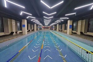 Una piscina techada larga con marcas claras para carriles e iluminación moderna en el techo.