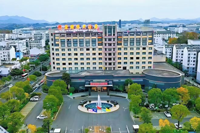 A multi-story hotel with a central courtyard, surrounded by trees and a parking area.