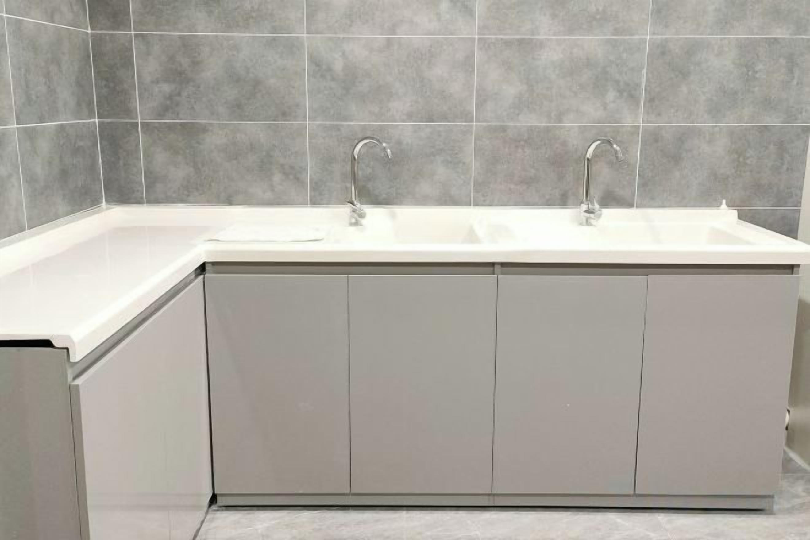 A modern kitchen with a double sink, white cabinets, and grey tiled backsplash.