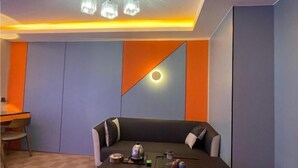 A modern room with a sofa, a table with a teapot, and a unique wall design.