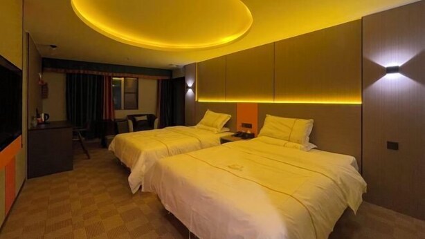 A hotel room with two beds, a desk, and a television.