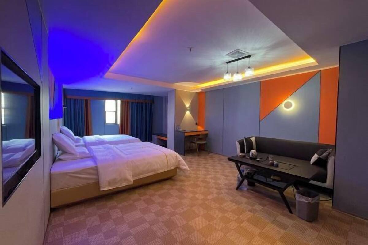 Een hotelkamer met een bed, een bureau, een bank en een prullenbak.
