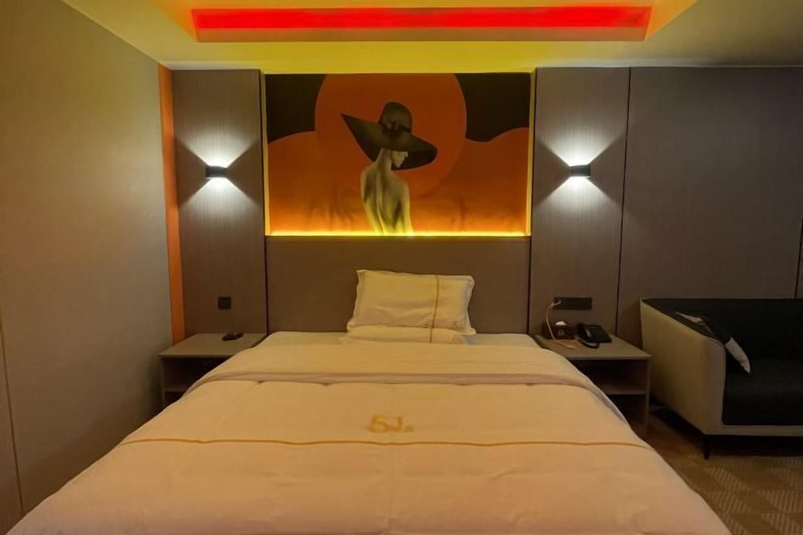 Una habitación de hotel con una cama grande, una mesita de noche, una lámpara, un sofá y una obra de arte colgada en la pared.