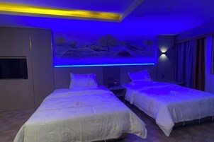 A hotel room with two beds, a mural on the wall, and a ceiling light.