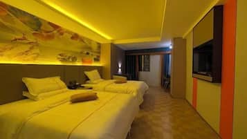 Habitación de hotel con dos camas, un mural en la pared, un televisor y un mostrador de recepción.