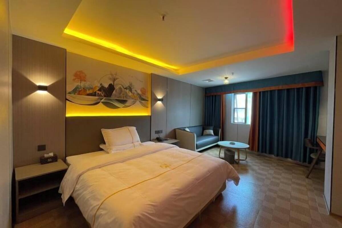 Een hotelkamer met een groot bed, een bank, een eettafeltje en een schilderij aan de muur.