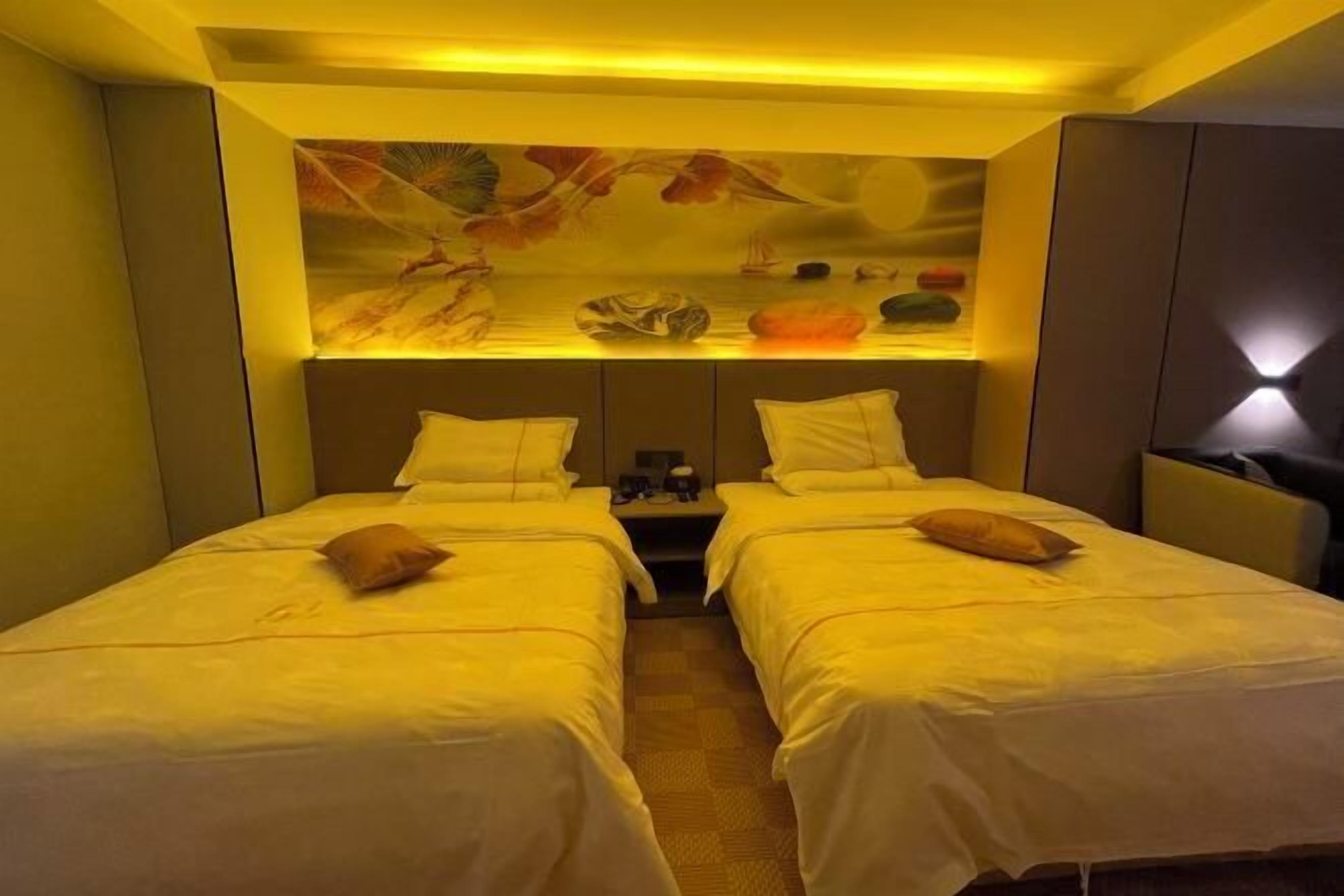 A hotel room with two beds, a nightstand, and a decorative wall.