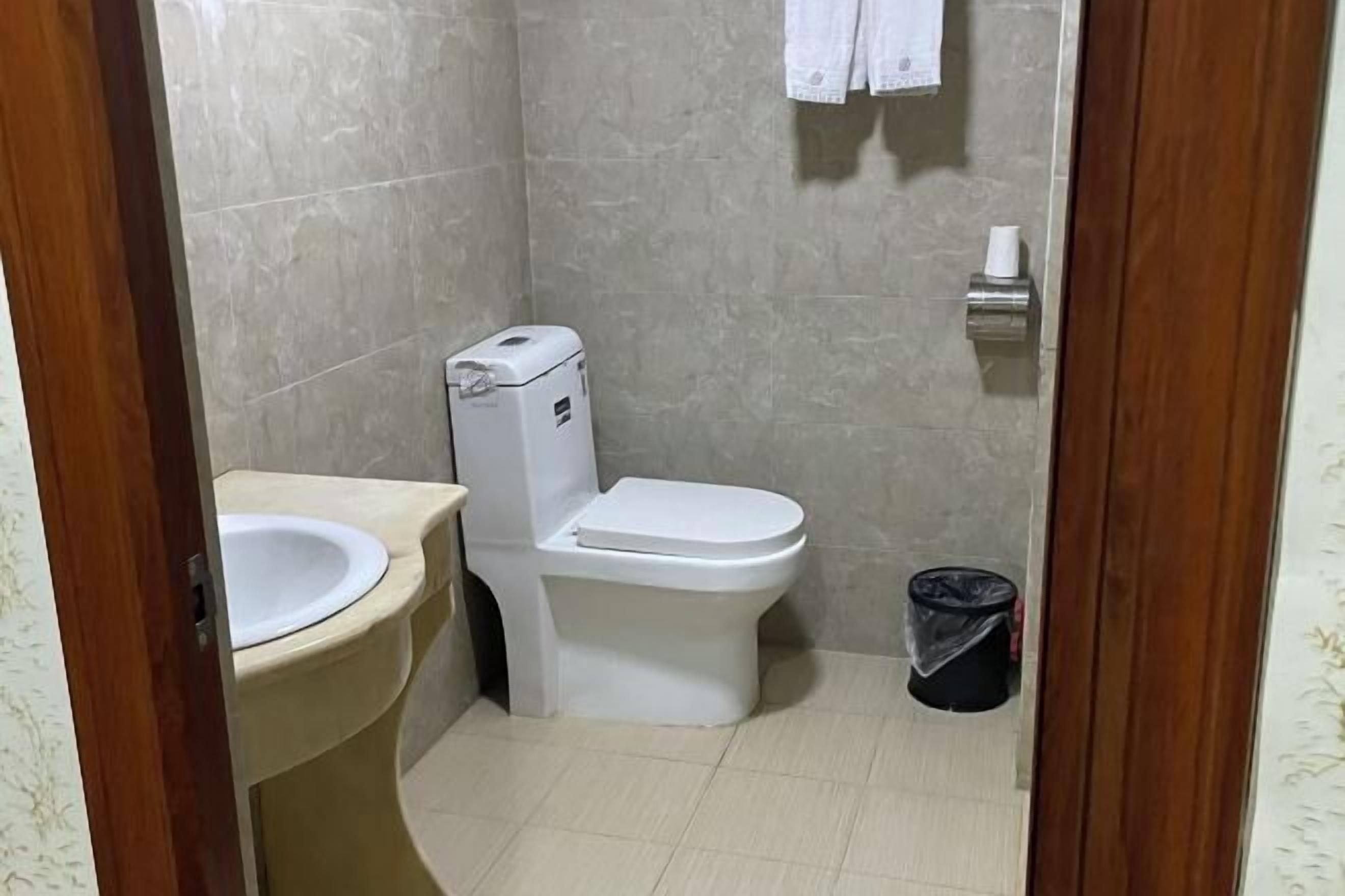 A small bathroom with a toilet, sink, and a trash bin.