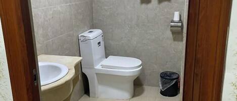 A small bathroom with a toilet, sink, and a trash bin.