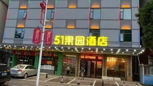 A hotel with a prominent yellow sign, multiple floors, and a parking area in front.