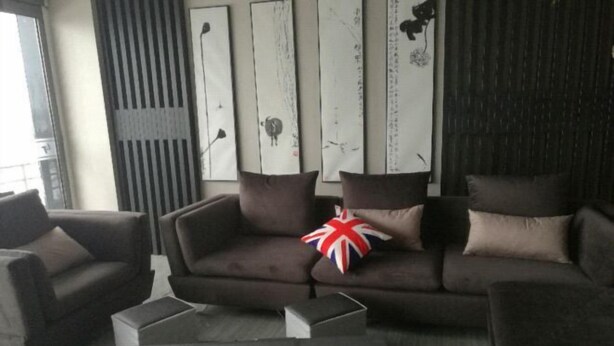 A modern living room with a dark brown sofa set, a small coffee table, and decorative pillows. - Langting Hotel (Dingxiang)
