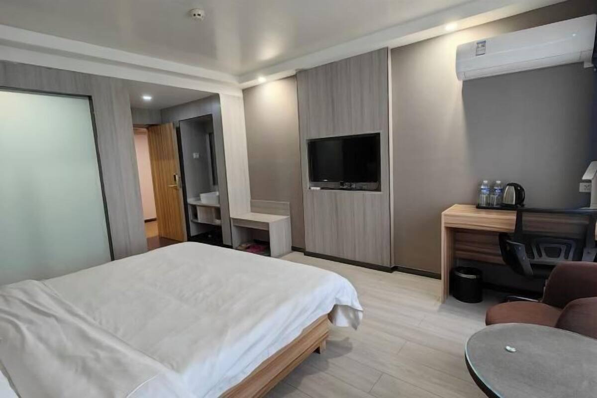 Een hotelkamer met een bed, een bureau, een televisie en een stoel.