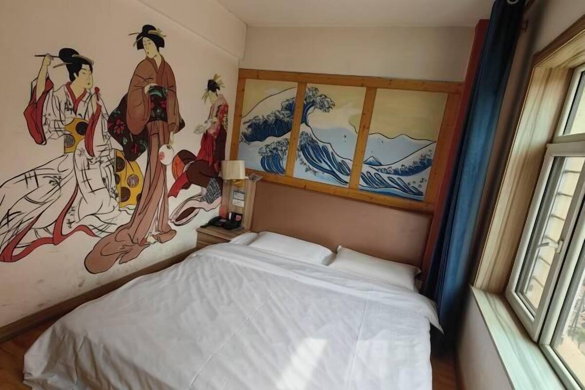Een hotelkamer met een bed, een muurschildering en een raam.