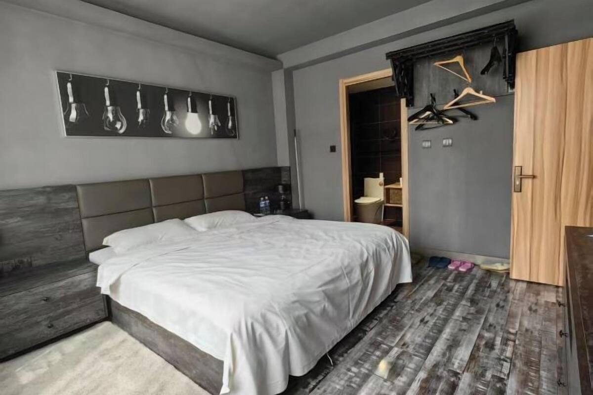 Een slaapkamer met een bed, een kledingkast, een spiegel en een deur naar een badkamer.