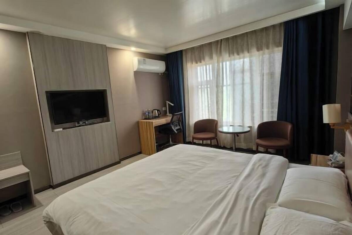 Een hotelkamer met een bed, een televisie, een bureau, twee stoelen en een klein tafeltje.