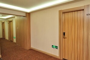 A hotel hallway with wooden doors, carpeted floors, and a visible emergency exit sign. - Langting Hotel (Dingxiang)