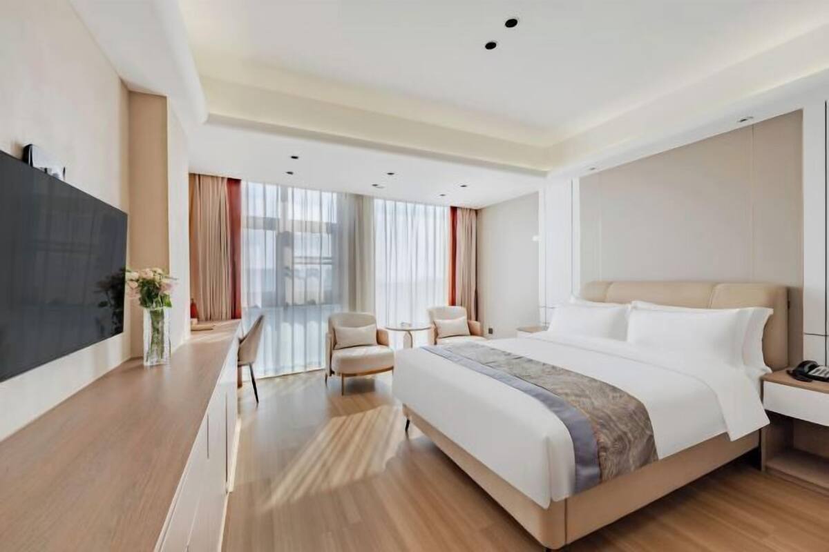 Een moderne hotelkamer met een groot bed, een bureau, een stoel en een televisie.