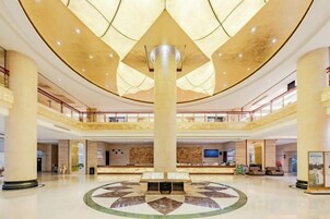 Un vestíbulo amplio con una columna central, suelo estampado y un mostrador de recepción.