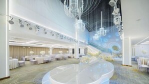 Un hall d’hôtel spacieux et moderne, doté d’une plateforme circulaire centrale, d’élégants lustres et d’un tapis à motifs.