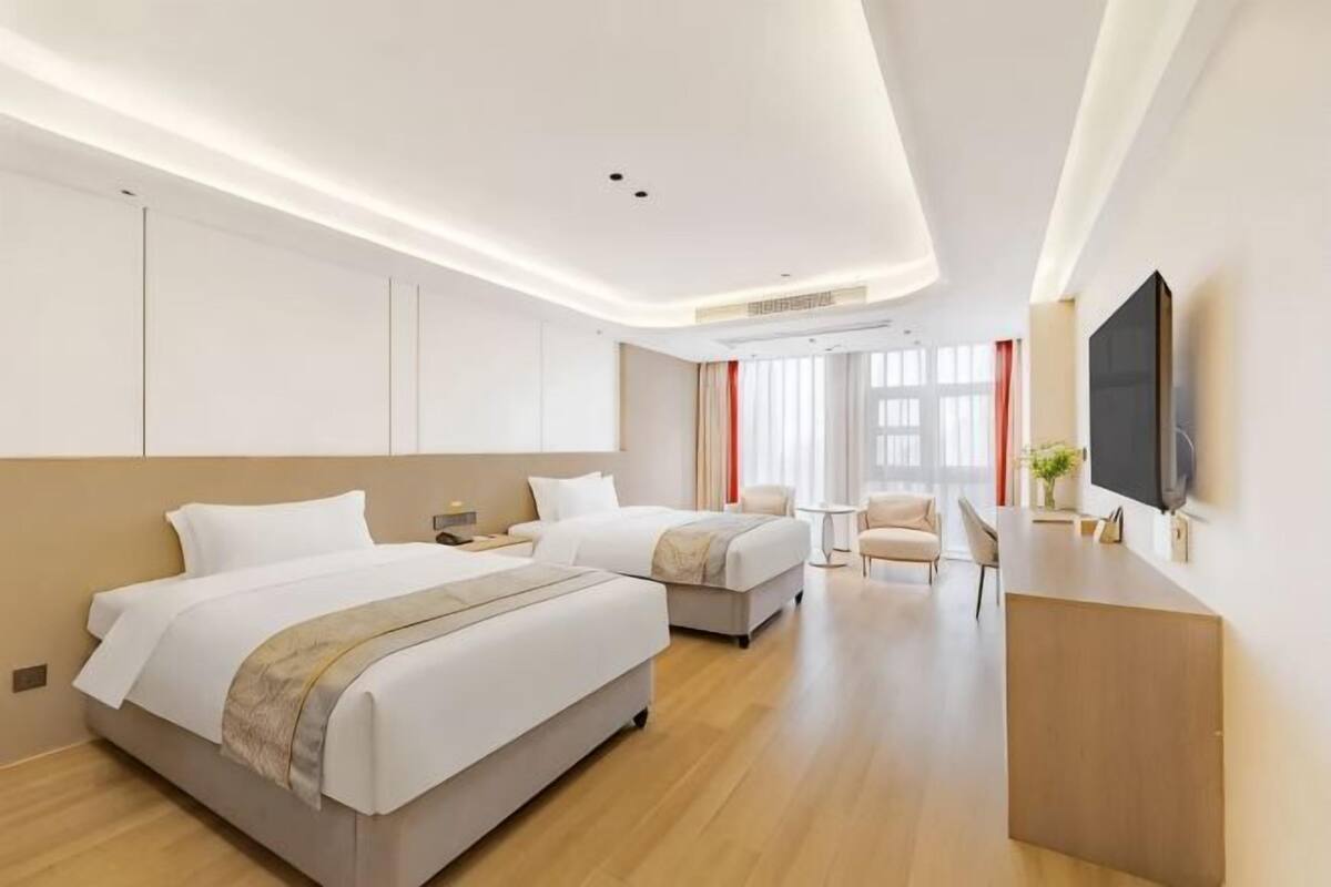 Een moderne hotelkamer met twee bedden, een televisie, een bureau en een groot raam.