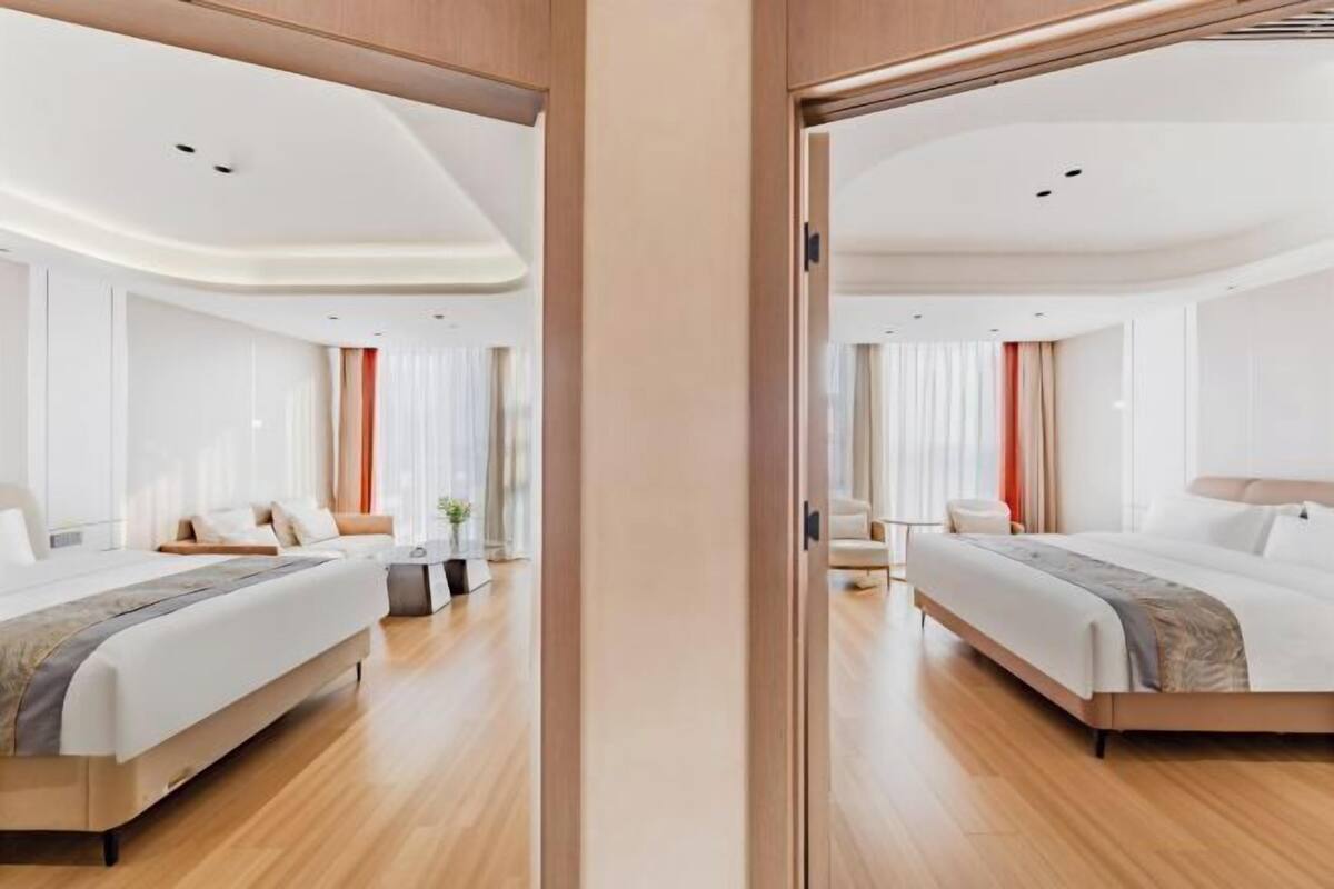 Een moderne hotelkamer met een groot bed, een bureau en een stoel. De kamer heeft een houten vloer en witte muren.