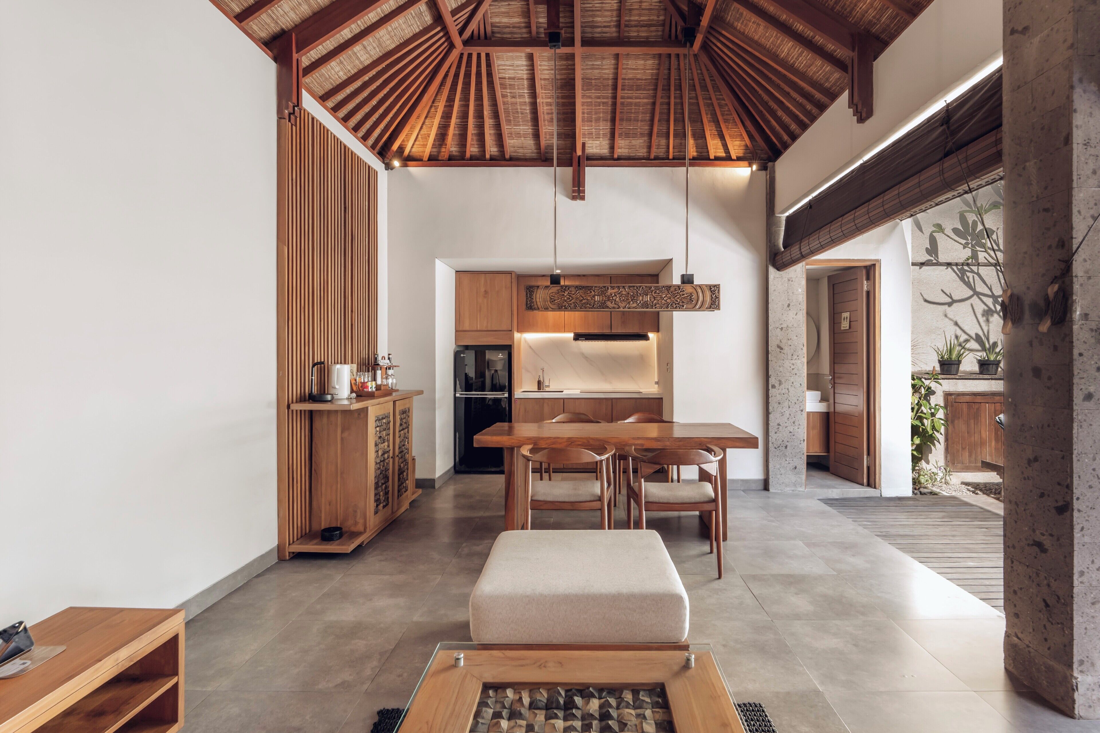 Um interior moderno com uma mesa de jantar de madeira, um sofá e uma área de cozinha.