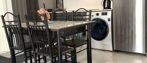 Una cocina moderna con armarios de madera oscura, un refrigerador de acero inoxidable, un microondas y una lavadora.
