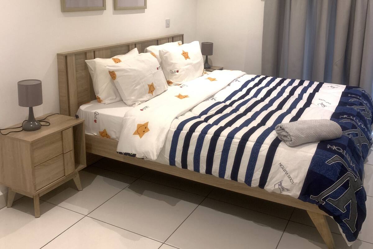 A neatly arranged bedroom with a bed, bedside tables, and a nightstand.