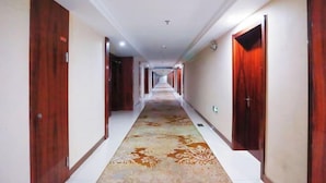 A long hallway with wooden doors on both sides and a patterned carpet. - Pizhou Melvo Hotel (Pizhou)