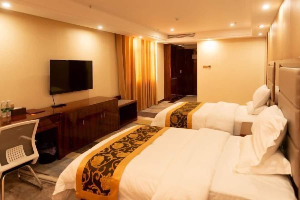 Une chambre d’hôtel avec deux lits, un bureau, une télévision et un escalier menant à une autre pièce.