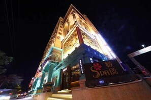 A hotel with a prominent entrance, illuminated signage, and a well-lit facade.