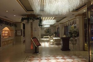 Eine Hotelhalle mit Empfangstresen, Sitzgelegenheiten und einer Kandelaber.