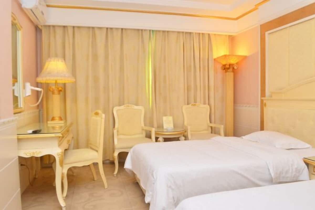Una habitación de hotel con dos camas, un escritorio, una silla, una mesa y una lámpara.