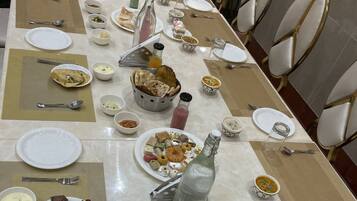 Una larga mesa de comedor dispuesta con diversos platos, incluyendo fuentes de comida, tazones y botellas, probablemente en un comedor de hotel.