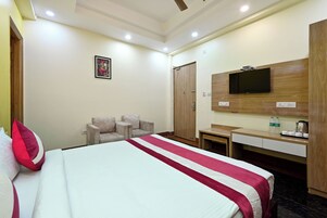 A hotel room with a bed, a desk, a TV, and a wardrobe.