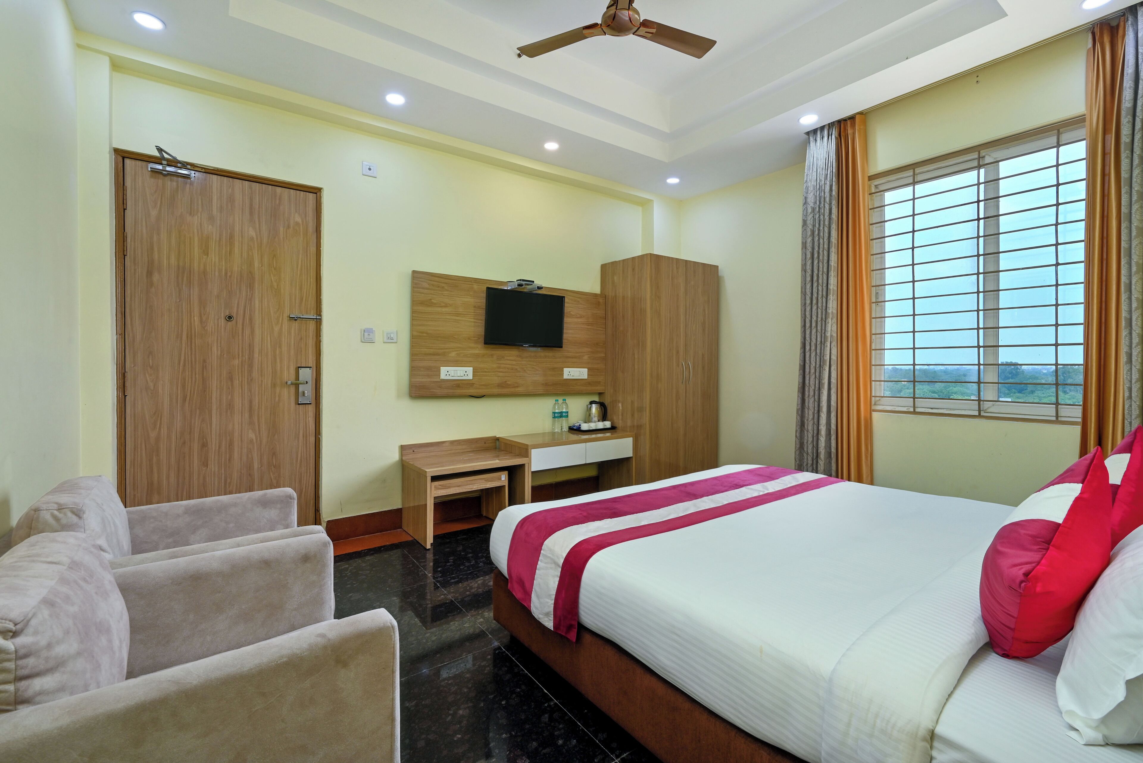 A hotel room with a bed, a desk, a wardrobe, a TV, and a window with curtains.