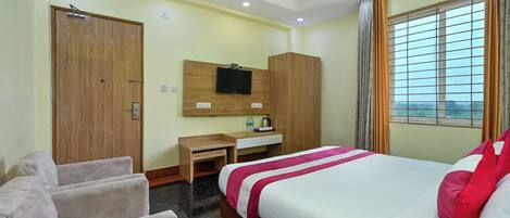 A hotel room with a bed, a desk, a wardrobe, a TV, and a window with curtains.