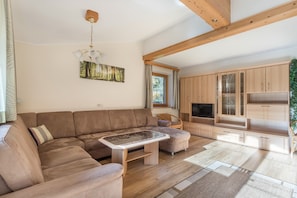 A spacious living area with a large sectional sofa, a wooden coffee table, and built-in wooden cabinets.
